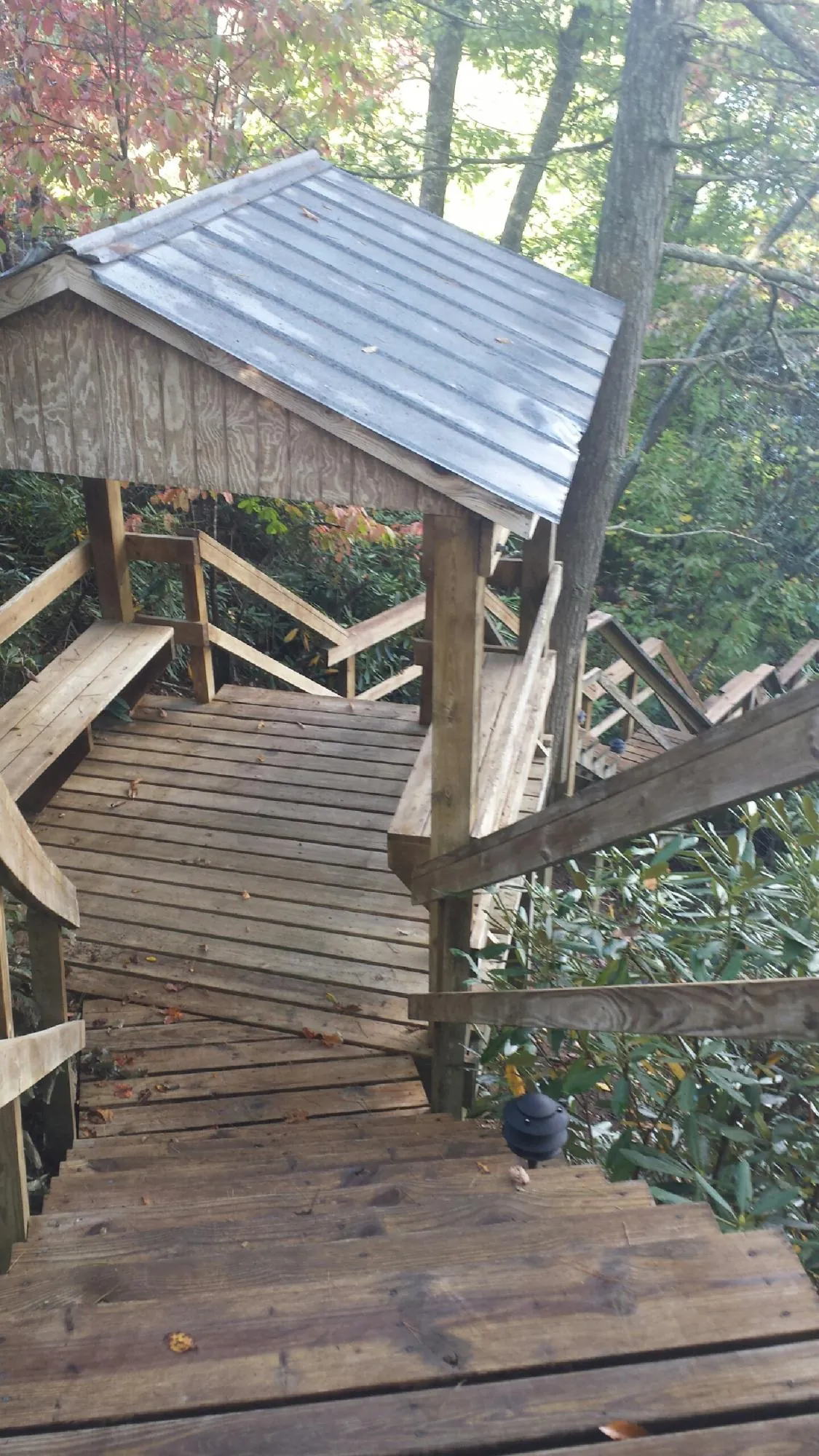 Metal roofed shelter over wooden steps on a wooded walkway — Skylight Repair & Installation work by our crew in Centreville